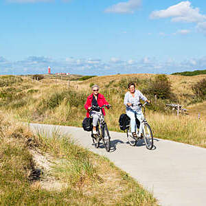 Two senior women cycling in dunes, Texel, Netherlands.