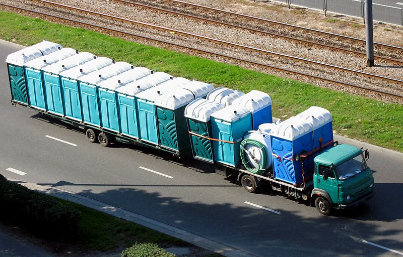 Truck driving with range of portable toilets.