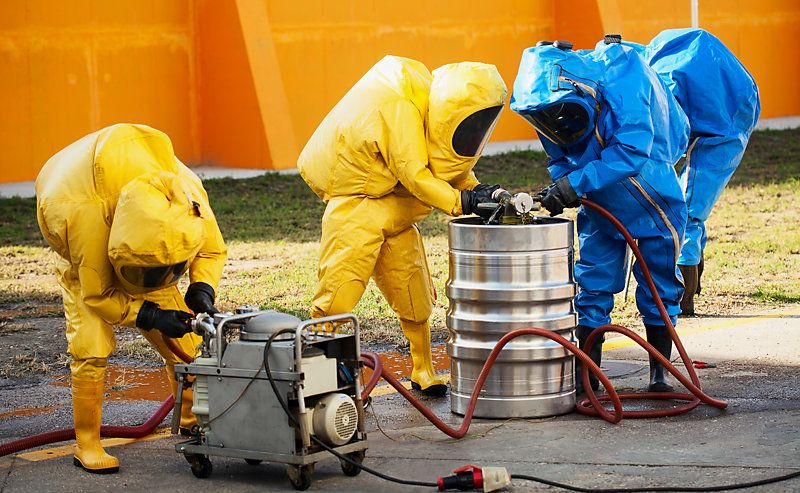 A team wearing hazmat suits and handling hazardous materials.