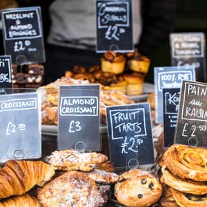 Close up color image depicting a large selection of artisan gourmet breads and pastries displayed on a bakery stall at Borough Market, London, UK, one of the most popular and oldest food markets in the world. Each item is labelled and priced. Room for copy space.