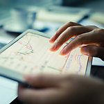 Close up on the hands of a woman, analyzing graphics on a digital tablet. 