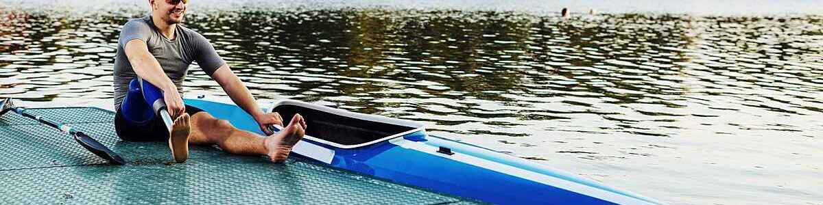 Smiling man who has a prosthetic leg, is sitting next to his kayak.