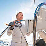 Blonde female skipper sailing on a sailboat.