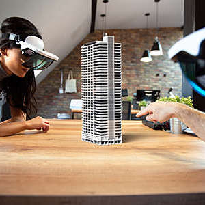 Two people work on a virtual 3D building using augmented reality glasses.