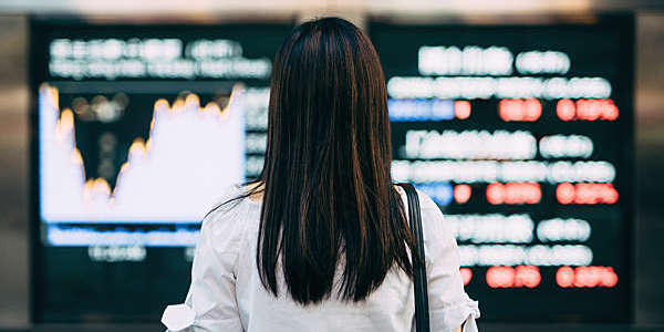 Back view of woman looking a stock exchange screens.