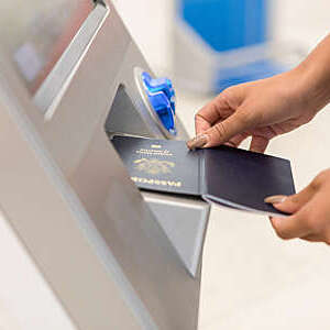 Close view of a woman’s hands scanning an e-passport at an airport biometric kiosk.