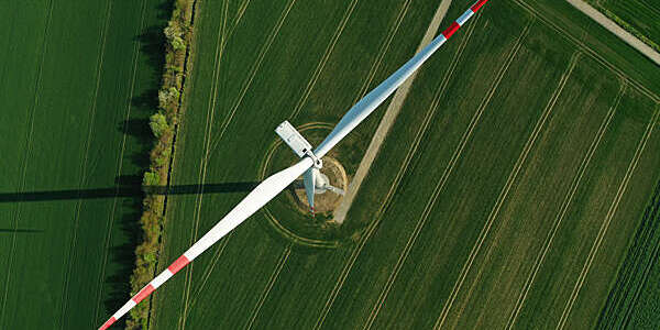 Aerial view of wind turbine with shadow on agricultural field.