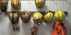 Safety helmets and gloves hang from a rack on a mining site